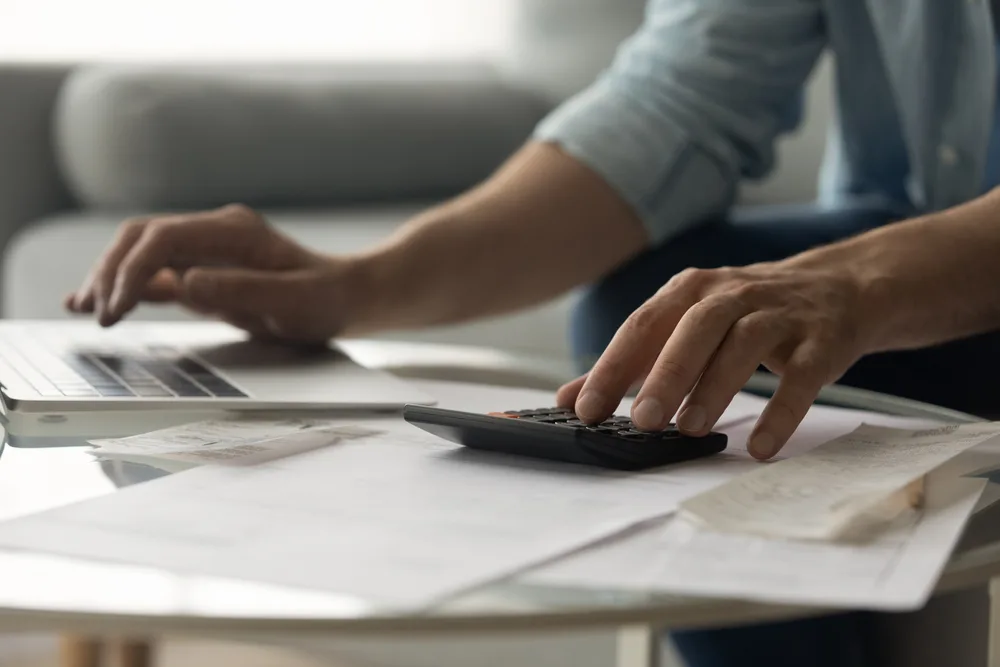 Someone using a laptop while working with a calculator. 